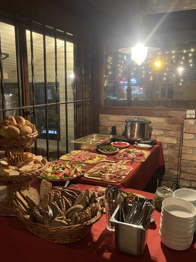 Reichhaltiges Buffet mit Brotkörben, Aufschnitt, Salaten und Gulaschtopf